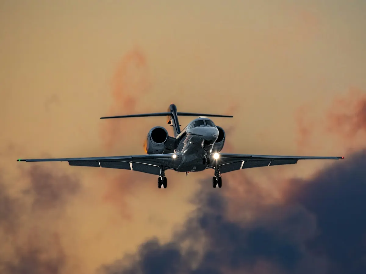 Midsize jet descending through warm evening cloud