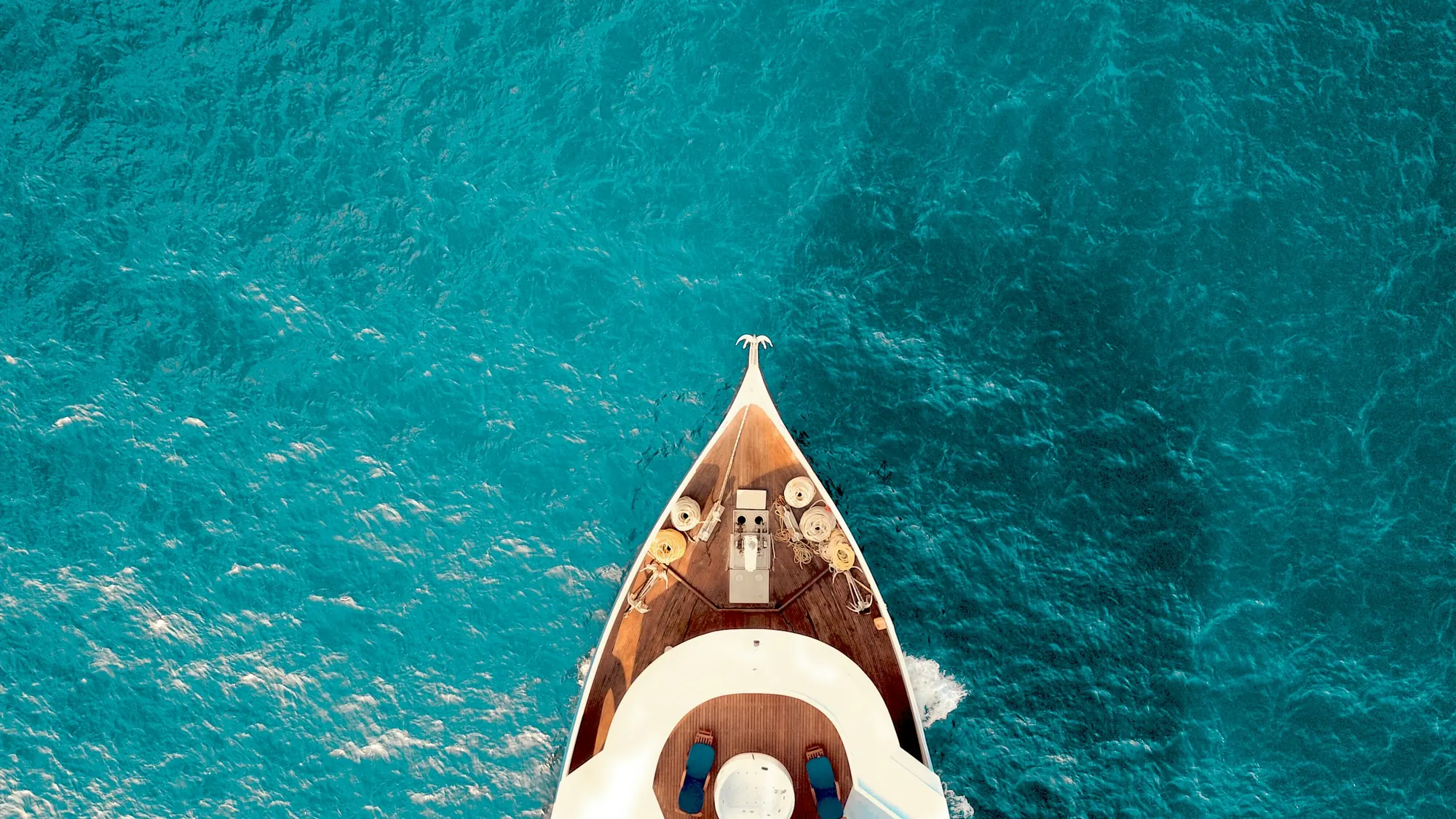 The bow of a yacht over clear turquoise water