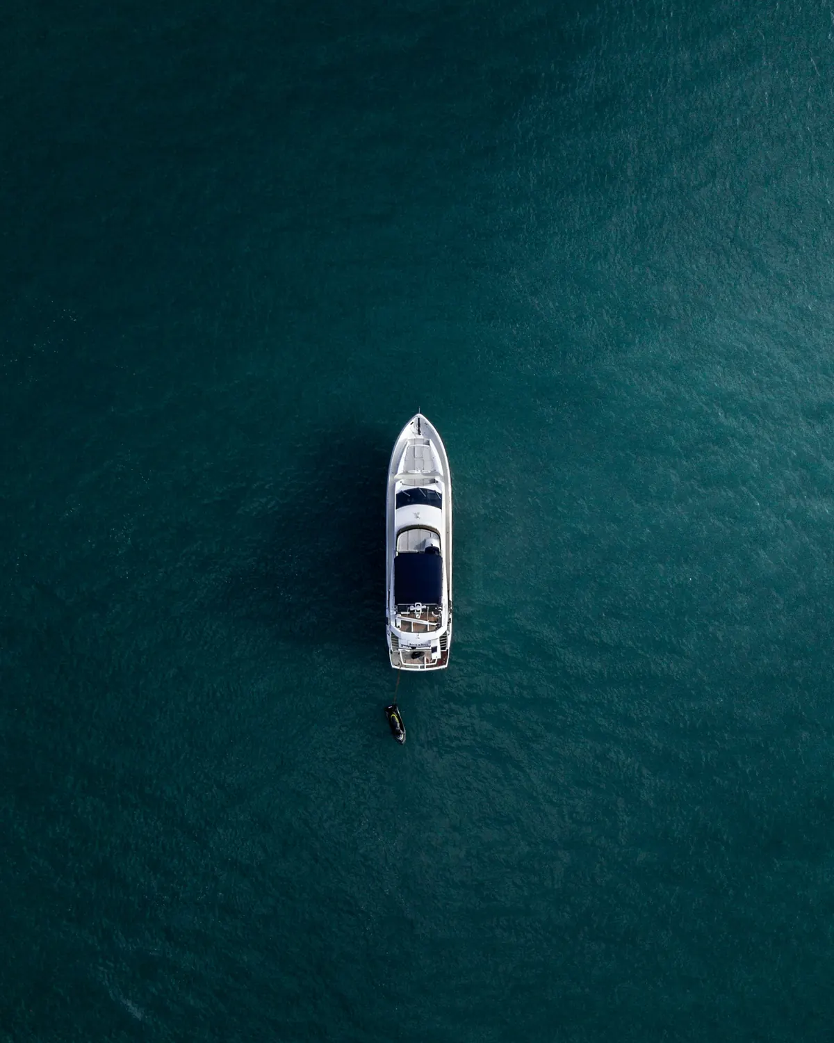 A motor yacht crossing deep blue water, seen from above